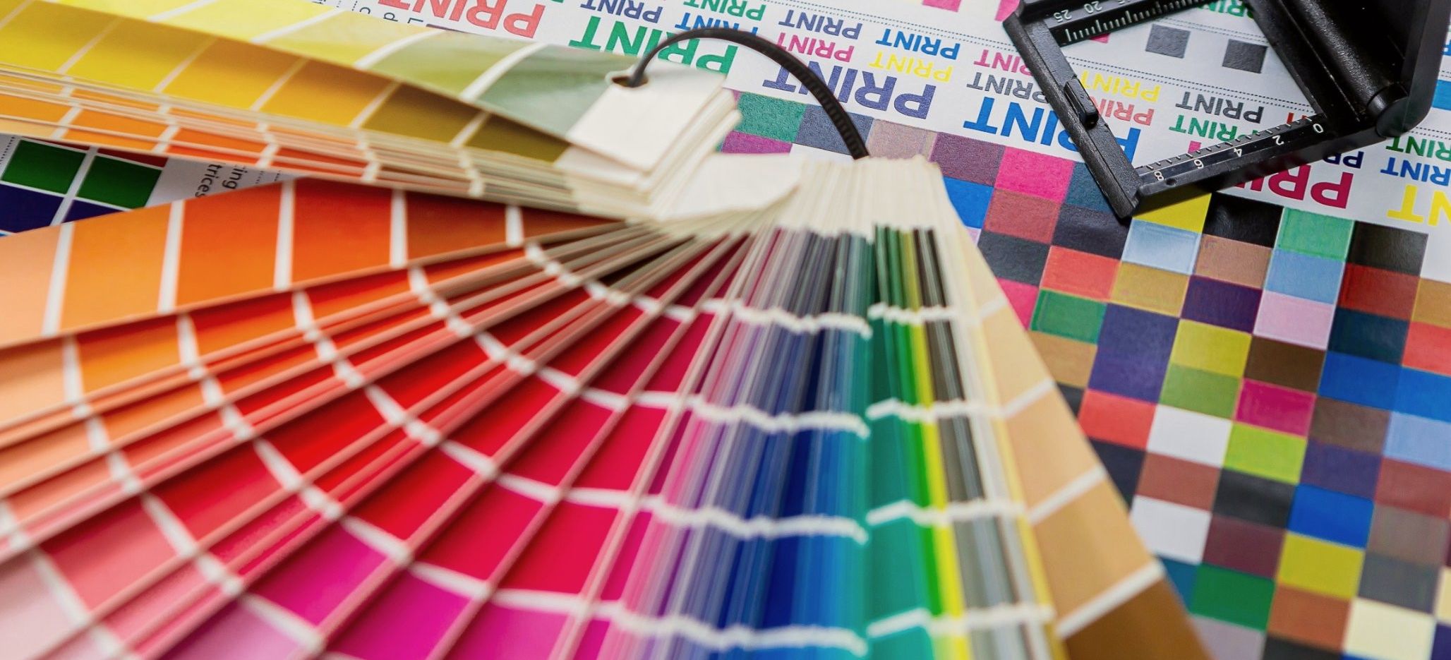 A spot-colour swatch guide and a linen tester resting on a printed colour test sheet