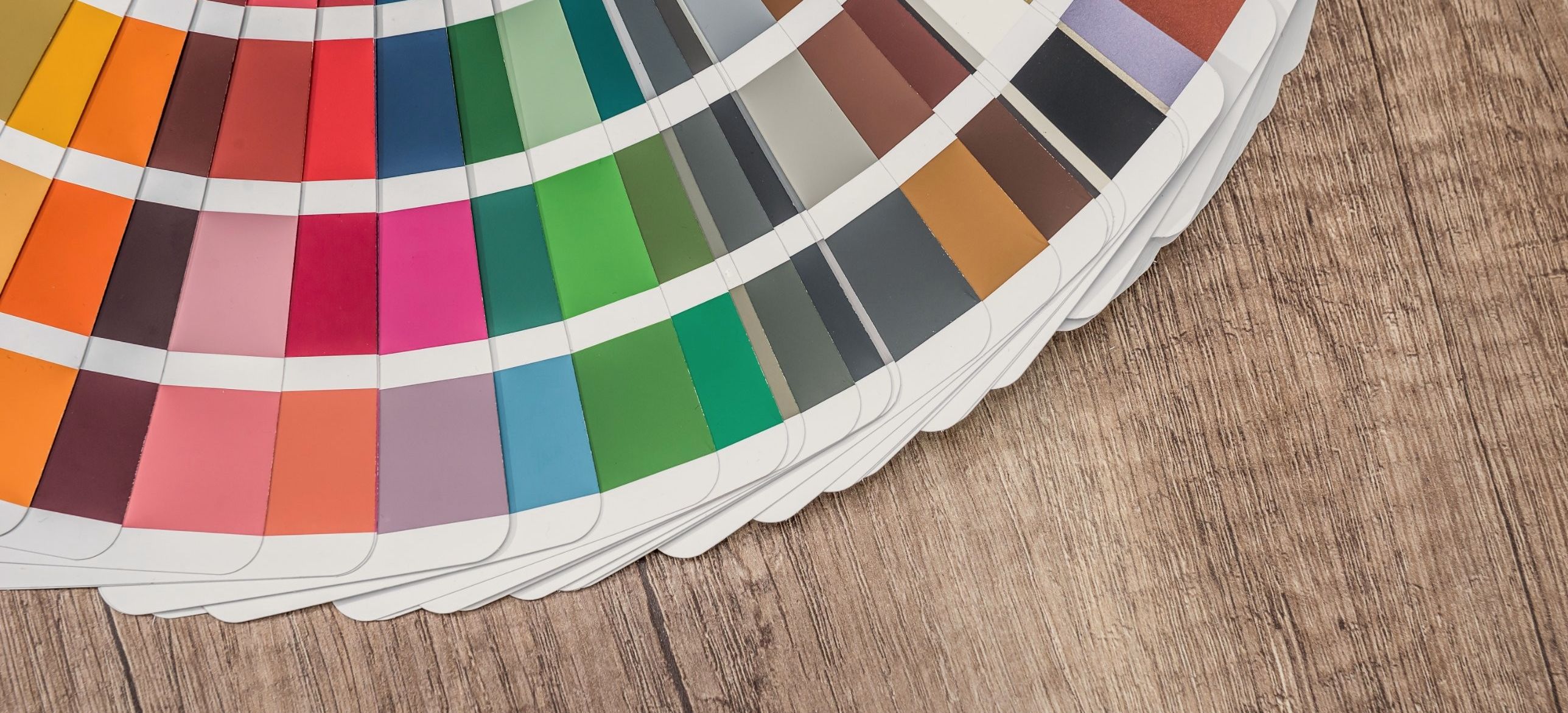 A colour swatch fan spread on an oak table